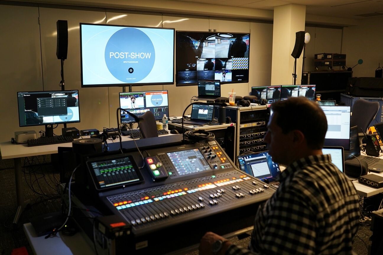 A man in a studio with multiple monitors and mixers