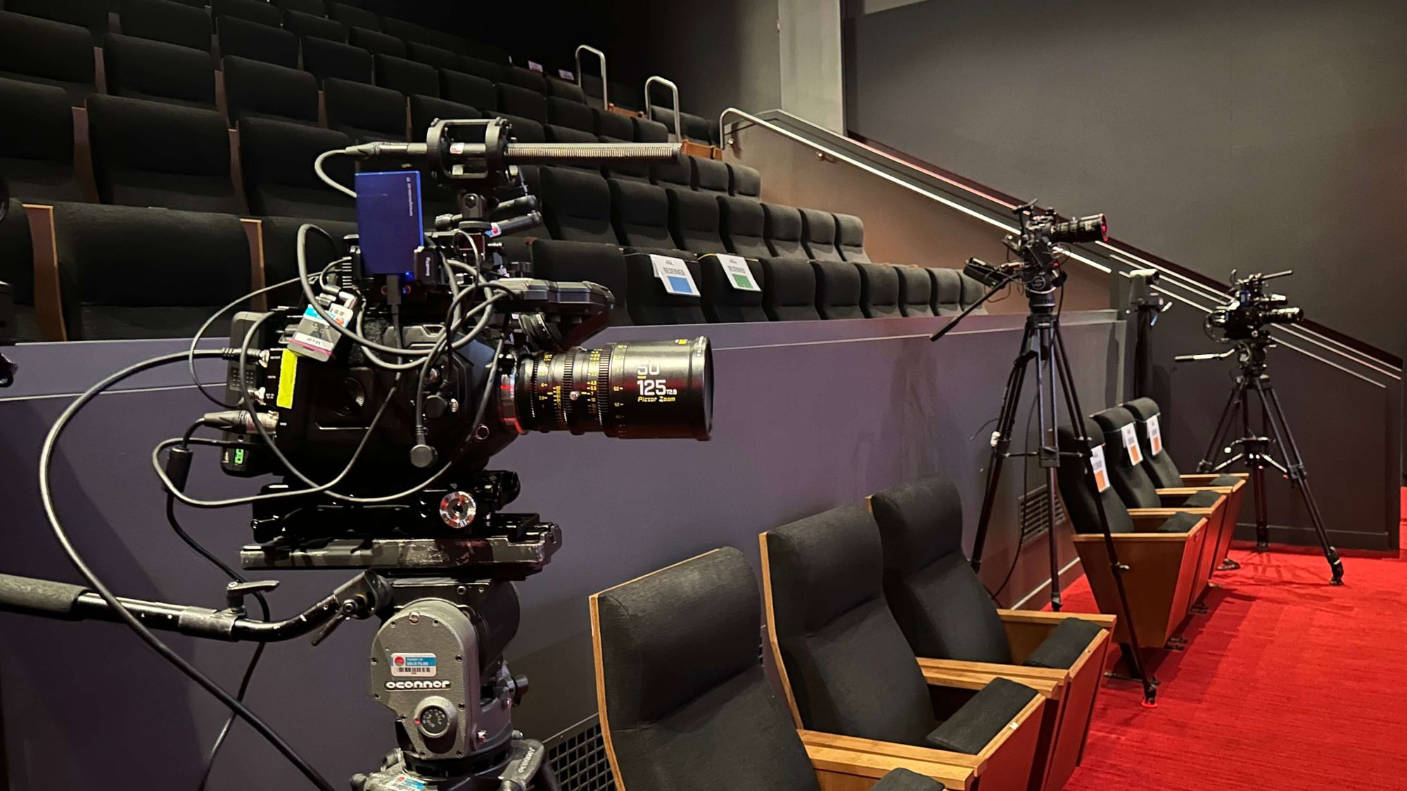 Several video cameras in an amphitheater seating area