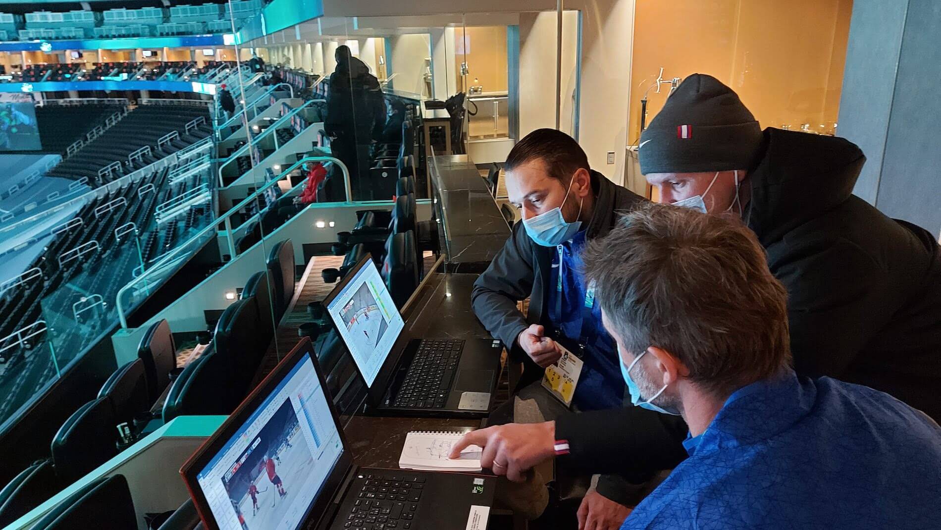 A few men watching hockey on laptop screens.